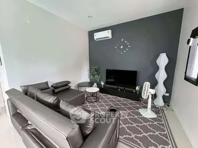 Modern living room with sleek furniture and stylish decor, featuring a wall-mounted air conditioner and contemporary lighting.