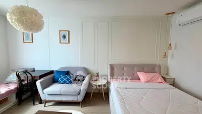 Chic studio apartment with modern decor, cozy seating, and stylish lighting, perfect for urban living.