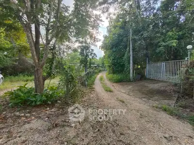 Charming rural property entrance with lush greenery and gravel path