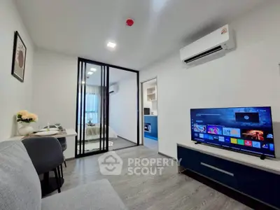 Modern living room with sleek design and glass partition leading to bedroom, featuring a wall-mounted TV and air conditioning.