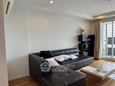 Modern living room with leather sectional sofa and sleek shelving unit.