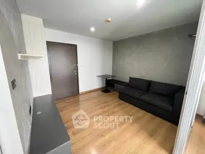 Modern living room with sleek design and wooden flooring, featuring a stylish black sofa and minimalist decor.