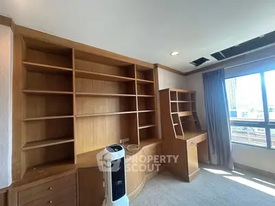 Spacious study room with built-in wooden shelves and large window view