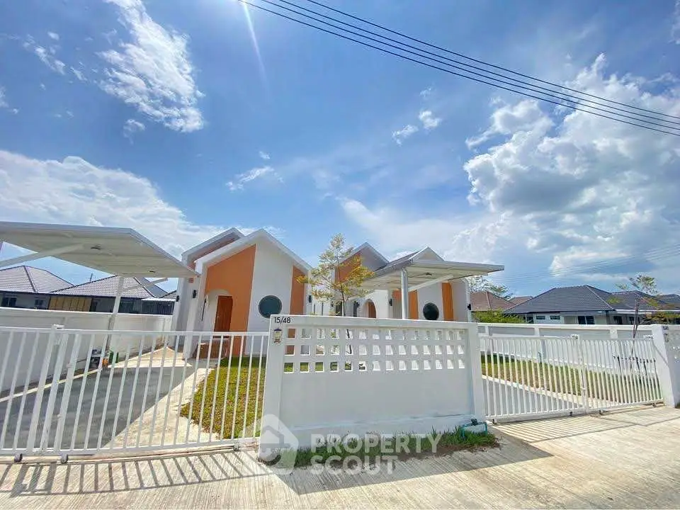 Charming suburban home with white fence and clear blue sky, perfect for family living.