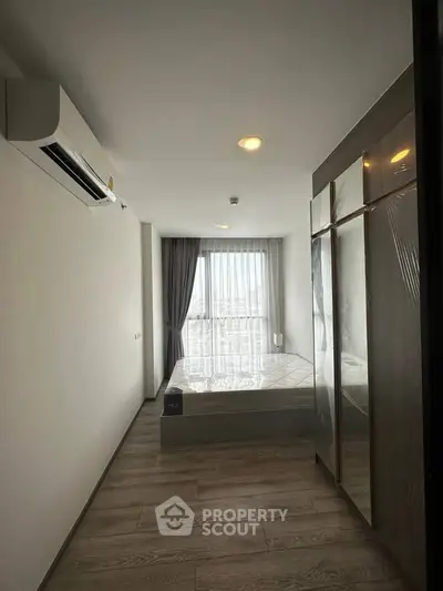 Modern bedroom with large window and sleek design, featuring air conditioning and ample storage space.