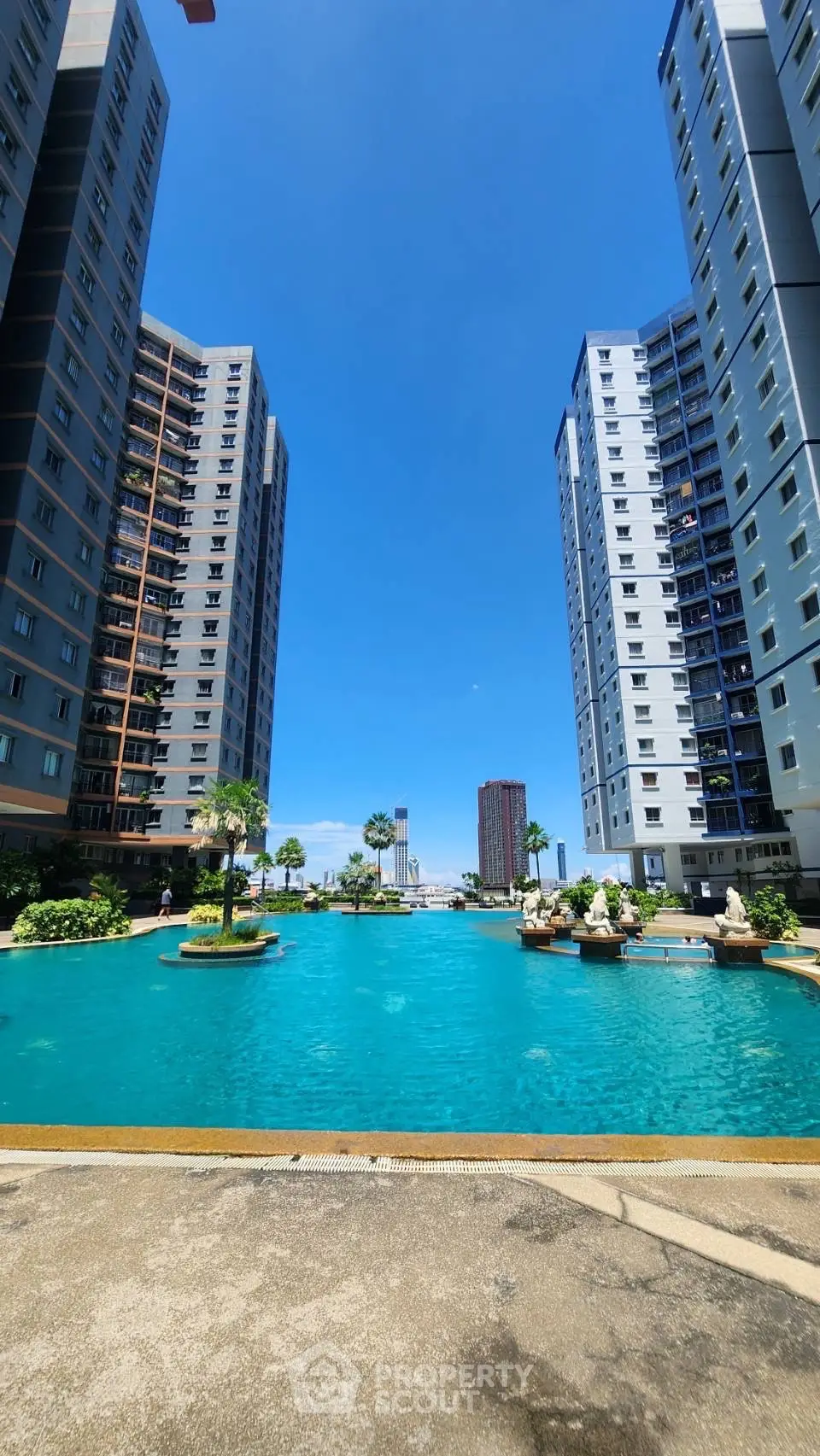 Luxurious residential complex with stunning pool and high-rise buildings under clear blue sky.