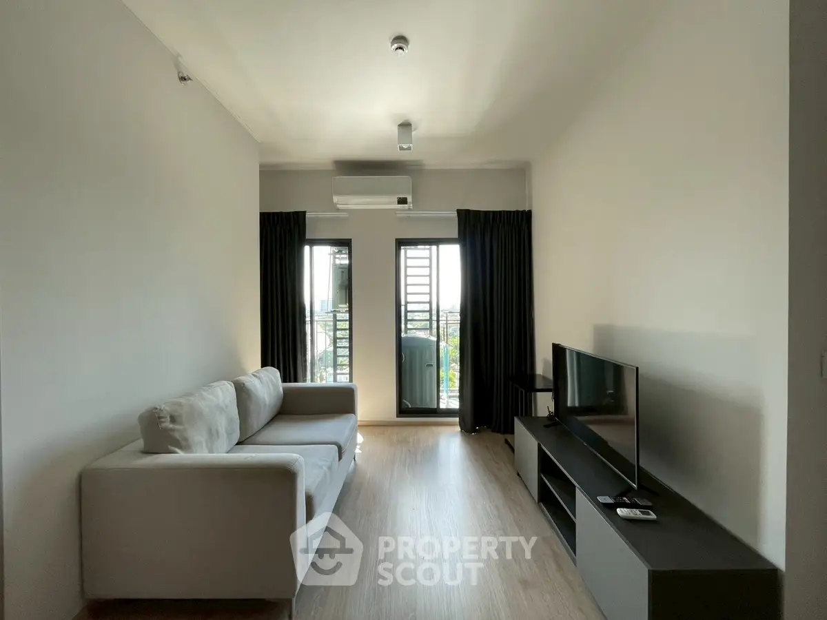 Modern living room with sleek furniture and balcony view in a stylish apartment.