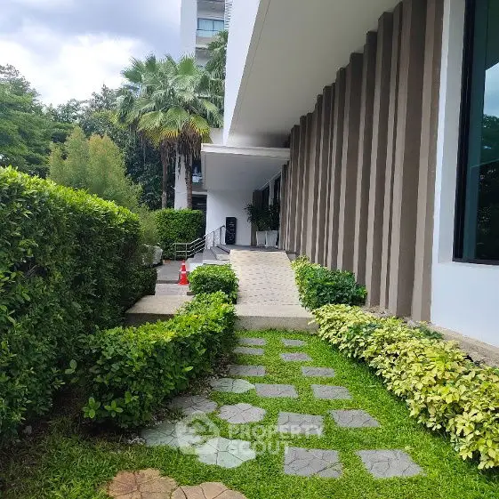 Modern building entrance with lush greenery and pathway