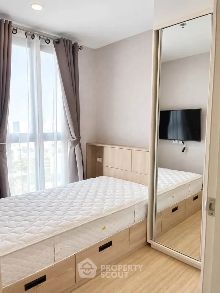 Modern bedroom with large window, mirrored closet, and wall-mounted TV in a stylish apartment.