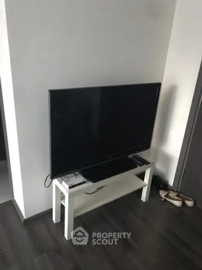 Modern living room corner with sleek TV setup on stylish white stand.