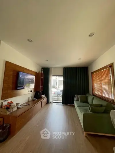 Modern living room with sleek wooden flooring and stylish green sofa