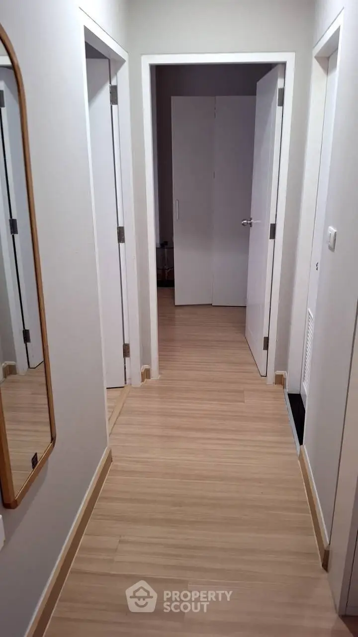 Modern hallway with wooden flooring and white doors in a stylish apartment.