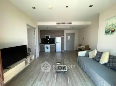 Modern living room with open kitchen, featuring sleek appliances and stylish decor.