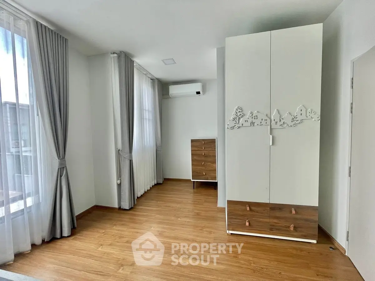 Spacious bedroom with elegant wooden flooring and modern wardrobe