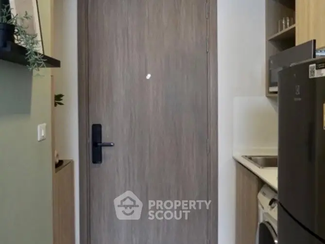 Compact kitchen with modern appliances and wooden cabinetry in cozy apartment.