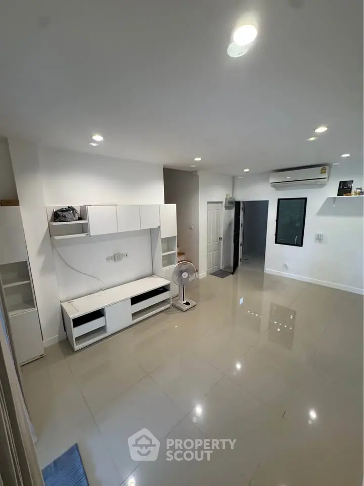 Spacious modern living room with sleek white furniture and glossy tiled floors.