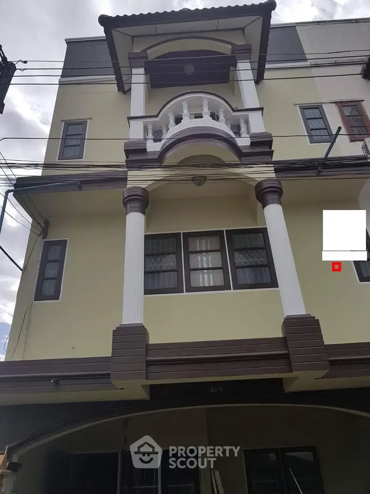 Elegant multi-story building with classic architectural columns and balcony, perfect for urban living.