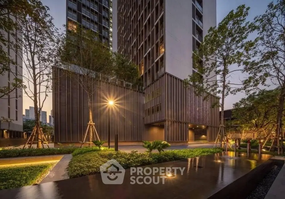 Stunning modern building exterior with lush landscaped garden and ambient lighting.