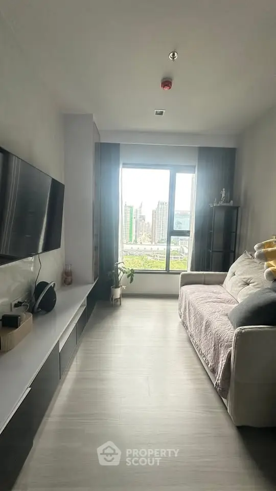 Modern living room with large window offering city view, sleek furniture, and cozy ambiance.