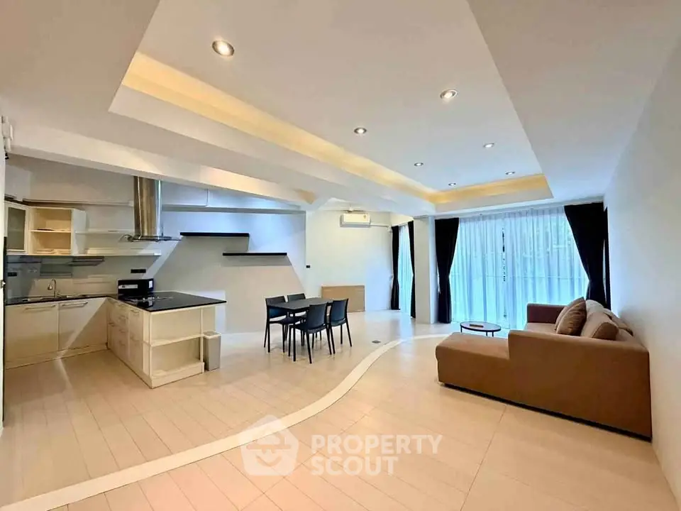 Spacious open-plan living room with modern kitchen and elegant lighting.