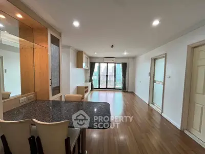 Spacious open-plan living room with wooden flooring and city view balcony.