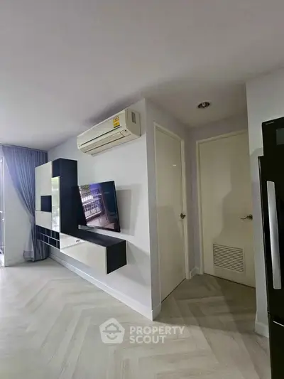 Modern living room with sleek entertainment unit and air conditioning in a stylish apartment.