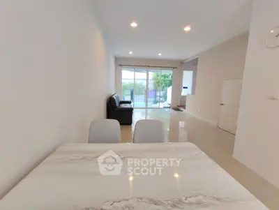 Spacious modern living room with elegant marble dining table and large windows.