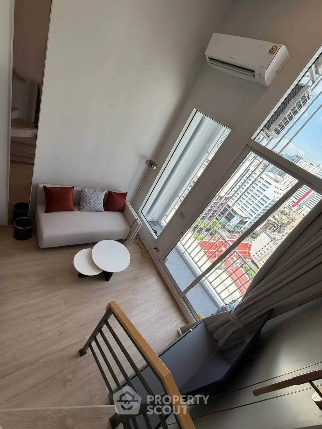 Modern loft apartment with high ceilings and large windows offering city views.