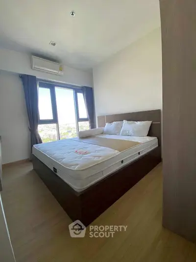 Modern bedroom with large window and wooden flooring, featuring a comfortable bed and air conditioning.