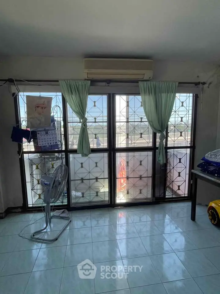 Spacious room with large windows and air conditioning, offering ample natural light and city views.