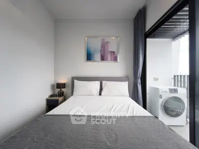 Modern bedroom with balcony access and washing machine, featuring sleek decor and natural light.