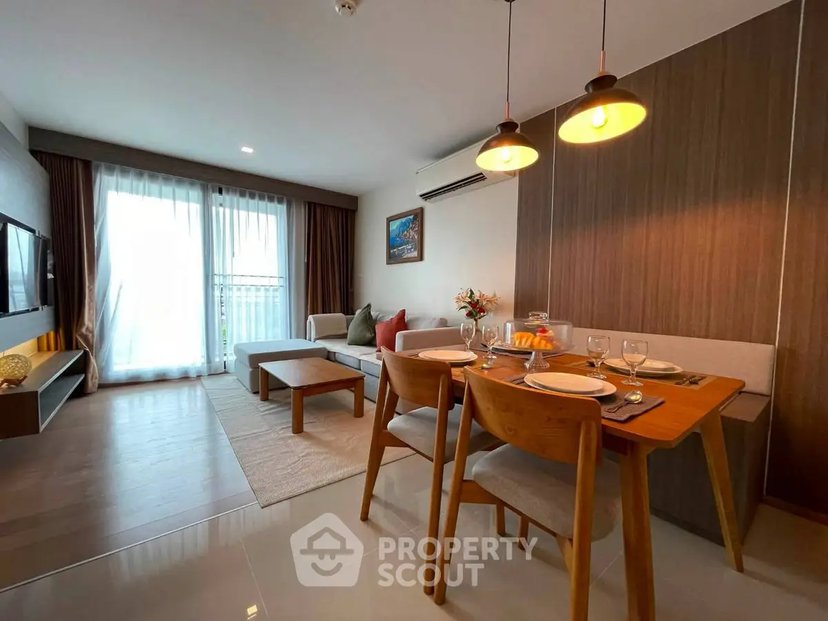 Modern living room with dining area, stylish decor, and natural light from large windows.
