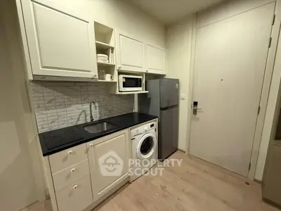 Compact kitchen with modern appliances and sleek cabinetry in cozy apartment.
