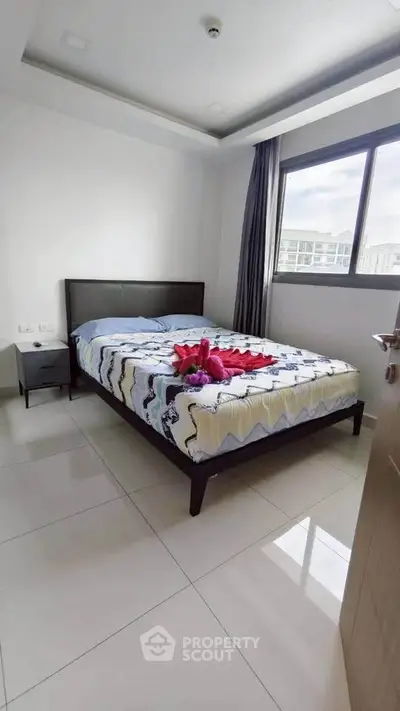 Modern bedroom with large window and stylish decor in a bright apartment.
