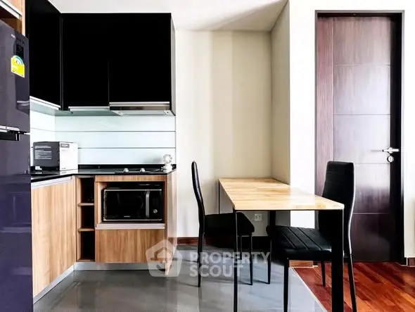 Modern kitchen with sleek cabinets, dining table, and appliances in a stylish apartment.
