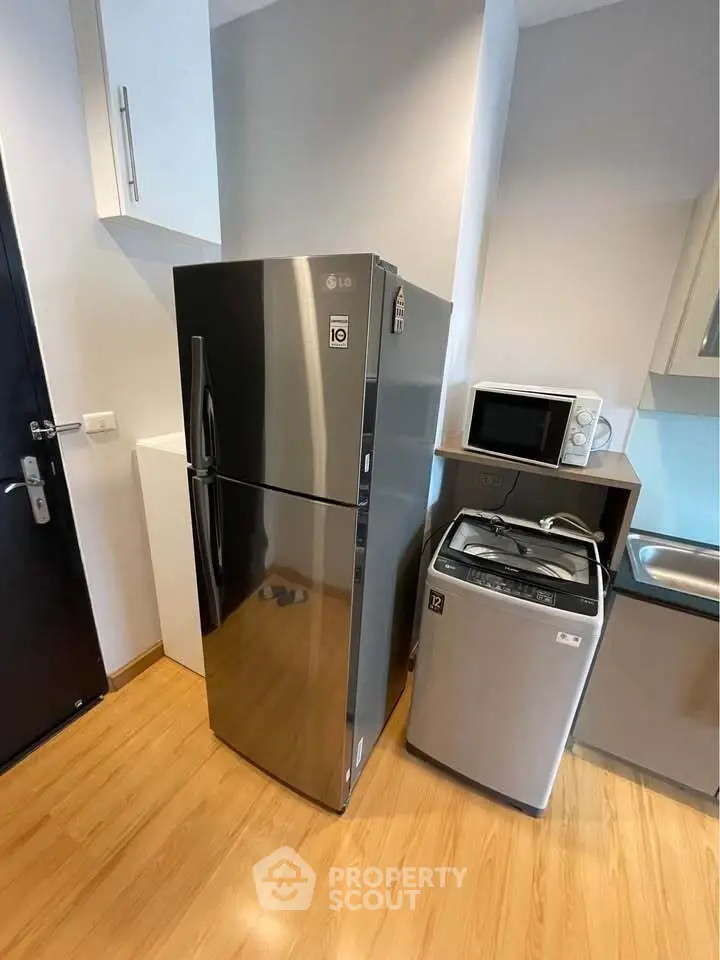 Modern kitchen with sleek appliances including fridge, microwave, and washing machine.