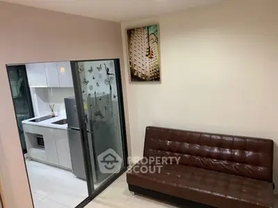 Modern living room with leather sofa and view into sleek kitchen