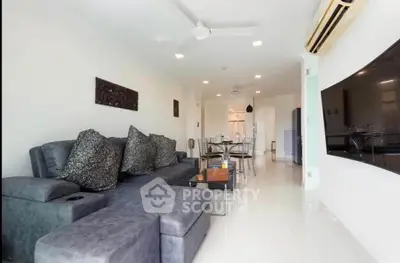 Spacious modern living room with elegant decor and open layout, featuring a sleek sectional sofa and dining area.