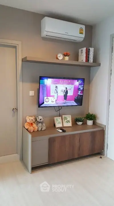 Modern living room with wall-mounted TV and air conditioning, featuring stylish decor and shelving.