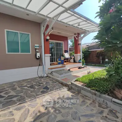 Charming house exterior with covered patio and lush garden, perfect for outdoor relaxation.