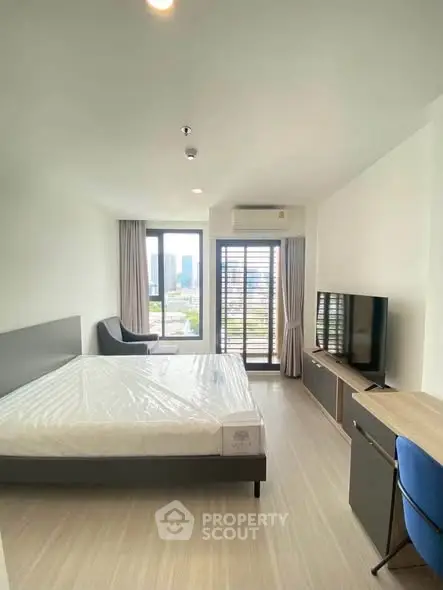 Modern bedroom with city view, large windows, and sleek furnishings in a high-rise apartment.