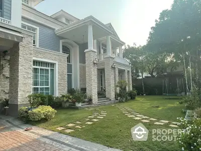 Elegant two-story house with stone facade and lush green garden