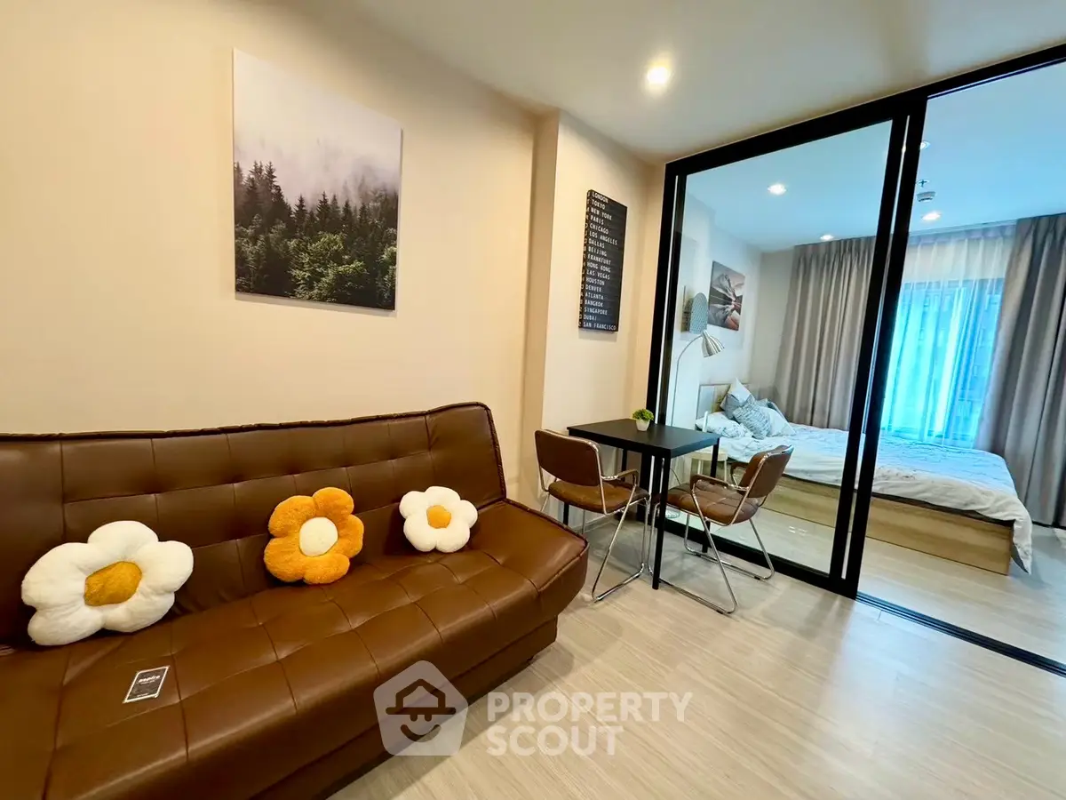 Modern apartment with cozy living room and stylish bedroom separated by glass doors, featuring chic decor.
