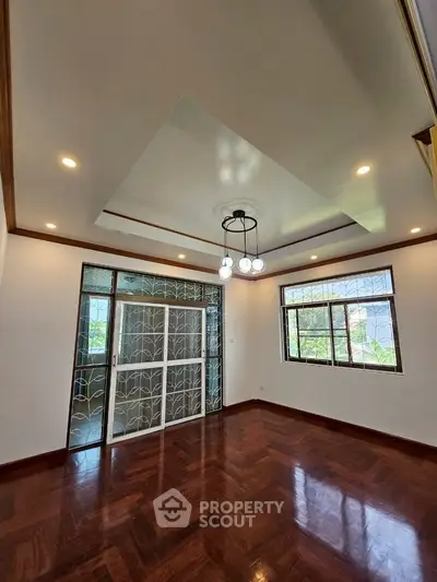 Spacious living room with elegant wooden flooring and modern lighting, perfect for family gatherings.