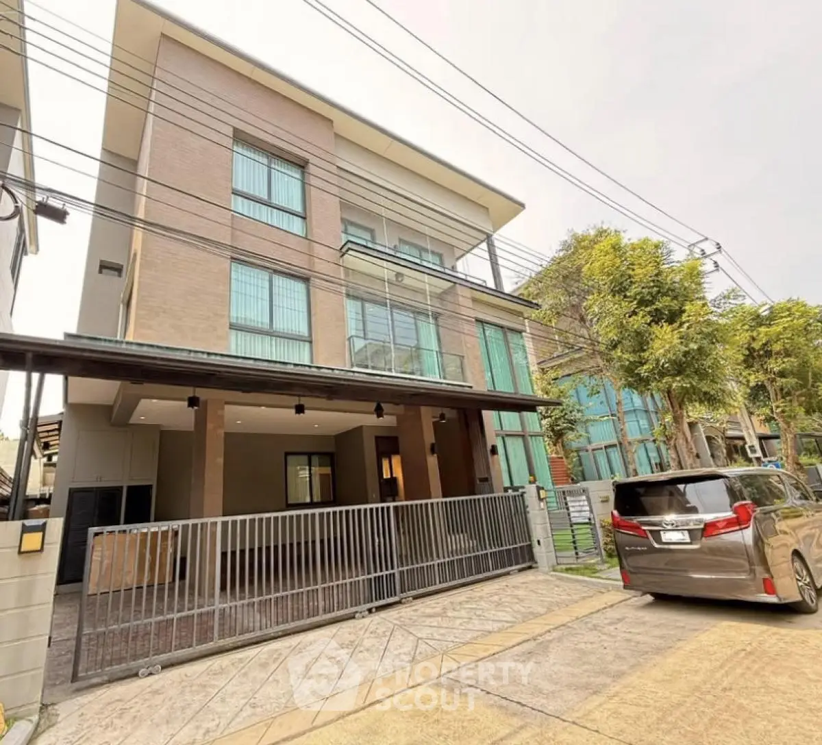 Modern three-story house with gated entrance and driveway in suburban neighborhood.