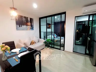 Modern open-plan living room with dining area and glass-walled bedroom, featuring stylish decor and cozy ambiance.