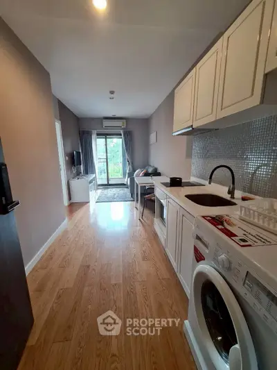 Modern apartment interior with open kitchen and living area, featuring hardwood floors and natural light.
