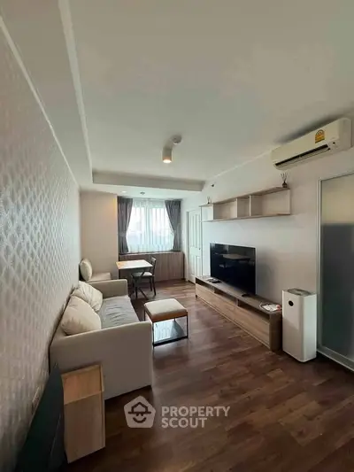 Modern living room with stylish furniture and wooden flooring, featuring a cozy sofa and large TV unit.