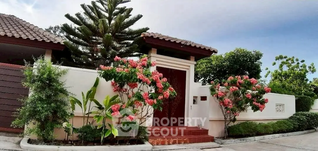 Charming residential entrance with lush garden and vibrant flowers, showcasing a serene and inviting atmosphere.