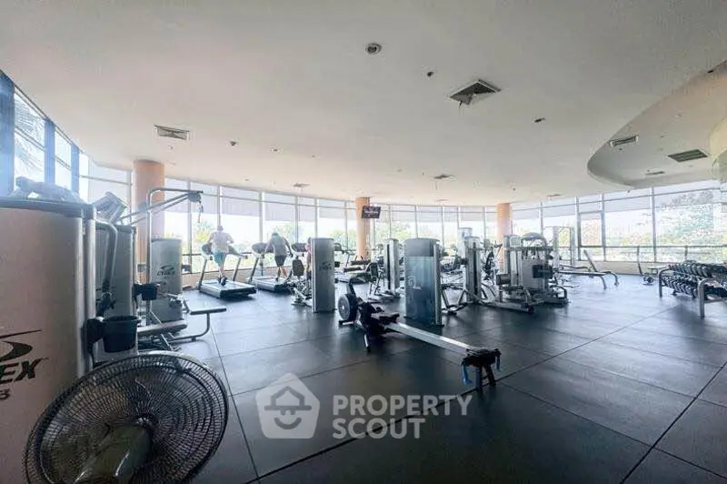 Spacious gym with modern equipment and large windows offering a scenic view, perfect for fitness enthusiasts.